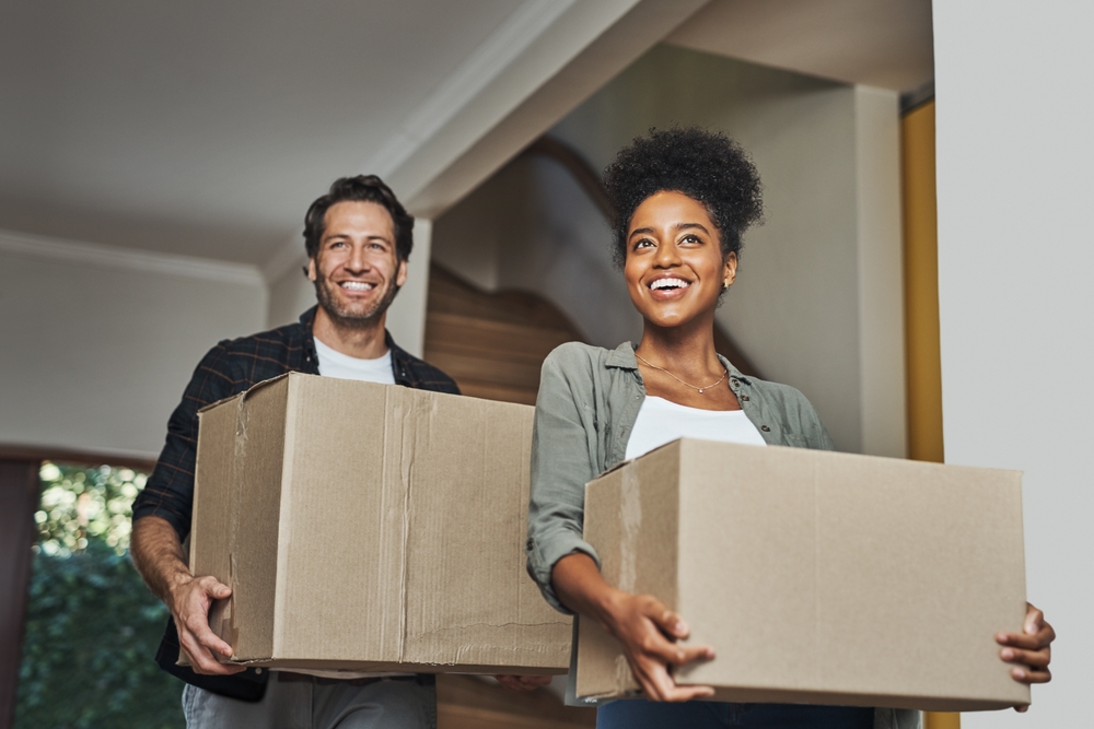 New,House,,Moving,And,Happy,Couple,Carrying,Boxes,While,Feeling